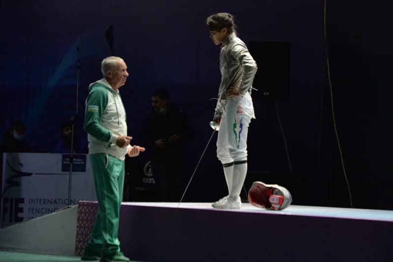 Fencing coach instructs athlete during competition