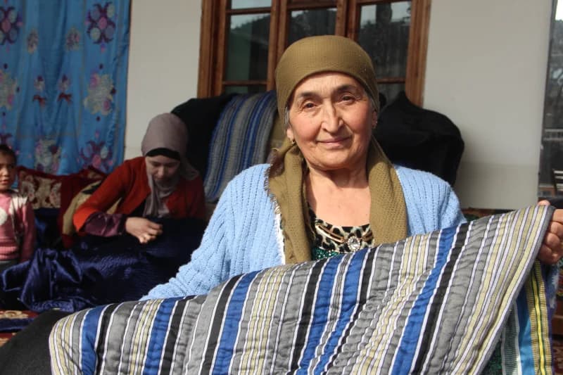 Elderly woman displaying traditional striped fabric