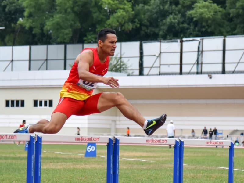 Athlete jumping over hurdle on track
