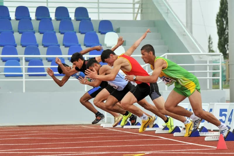 Спортсмены, начинающие бег на беговой дорожке