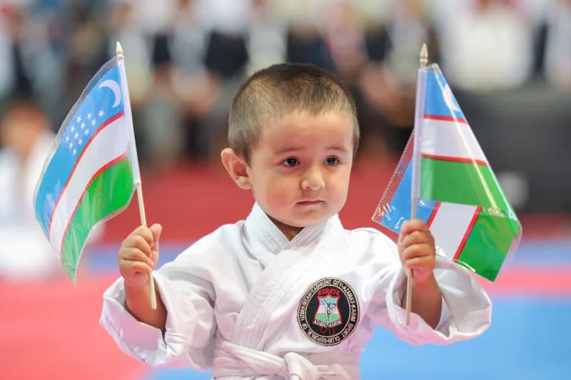 O‘zbekiston bayroqlarini ushlab turgan yosh karatechi