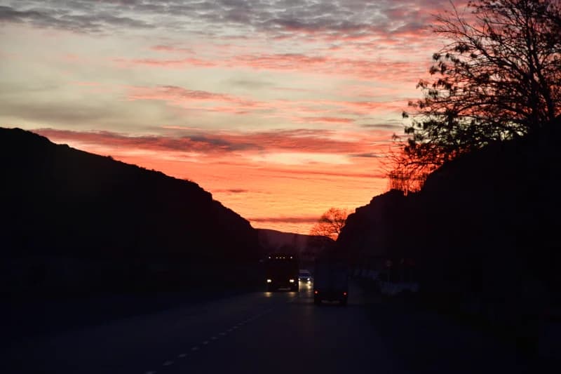 Vehicles driving on highway at sunset
