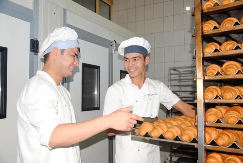 Bakers preparing fresh croissants in bakery