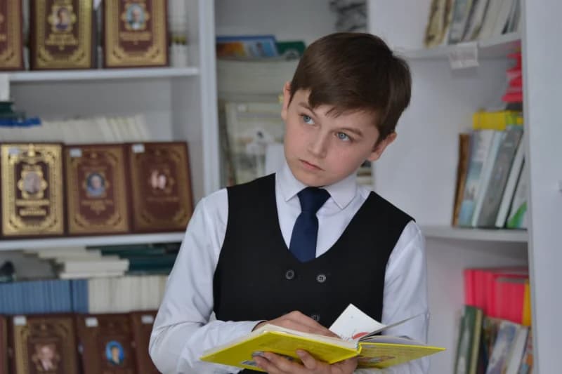 Schoolboy Reading Book in Library