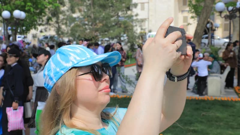 Женщина фотографирует в общественном парке