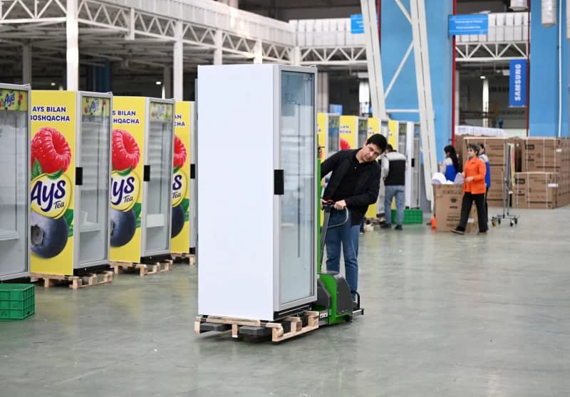 Worker moves refrigerator in factory