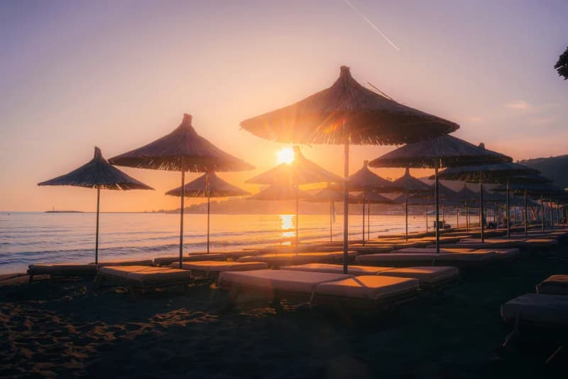 Quyosh plyaj soyabonlari uzra botmoqda