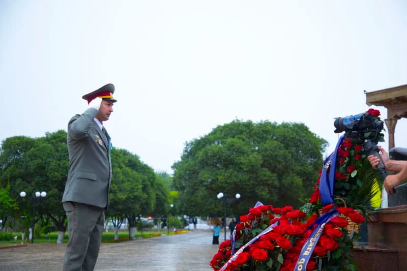 Military officer salutes memorial flowers
