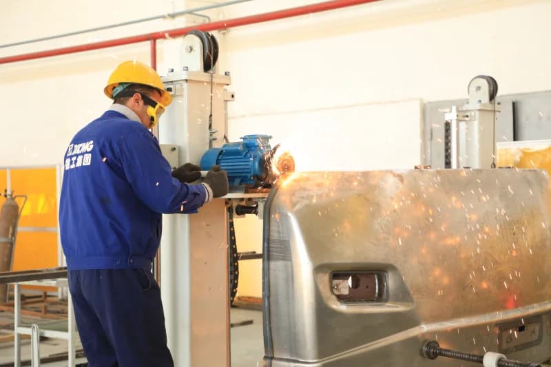 worker grinds metal in factory