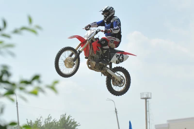 Motokrosschi qizil mototsiklda sakramoqda