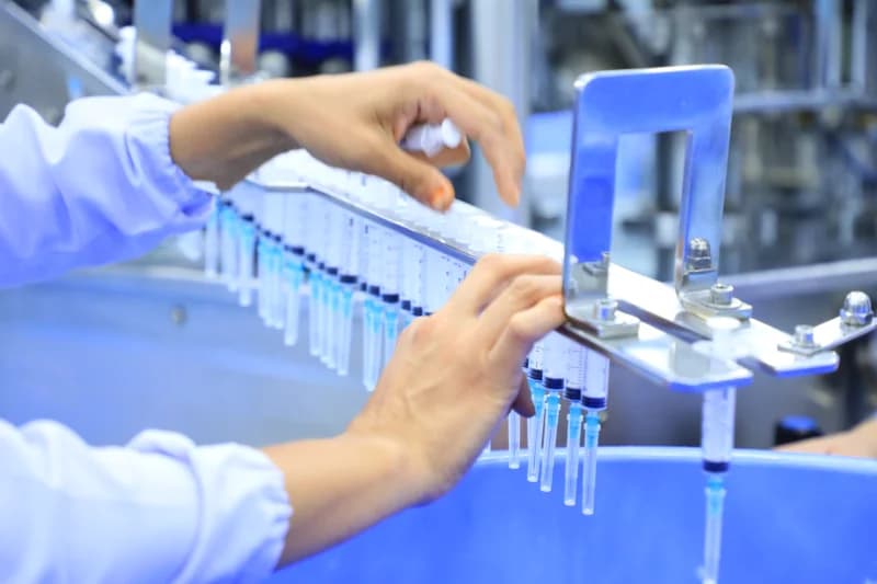 Worker inspects syringes on line