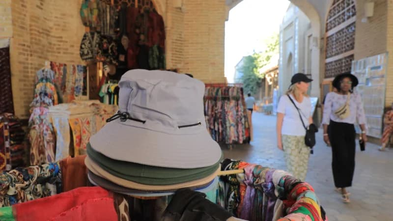 Turistlar bozorda tovarlarni koʻzdan kechiradilar