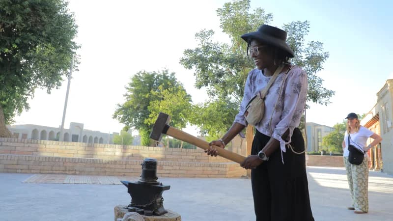 Woman strikes metal on anvil