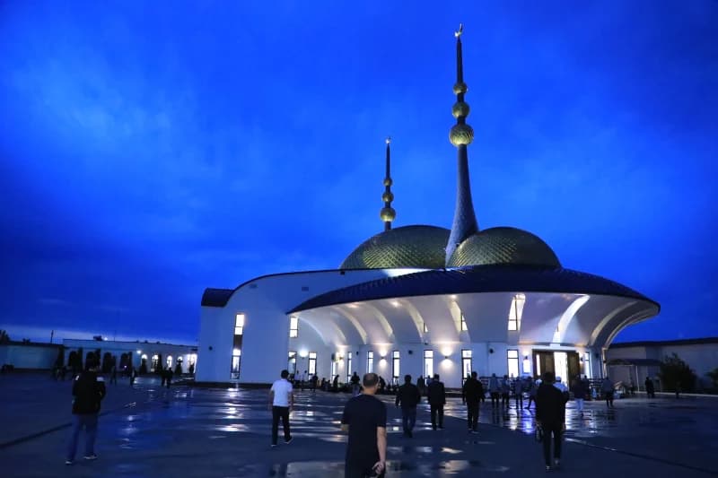 Люди идут к освещенной мечети
