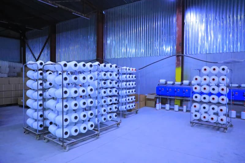 Workers organize white yarn spools