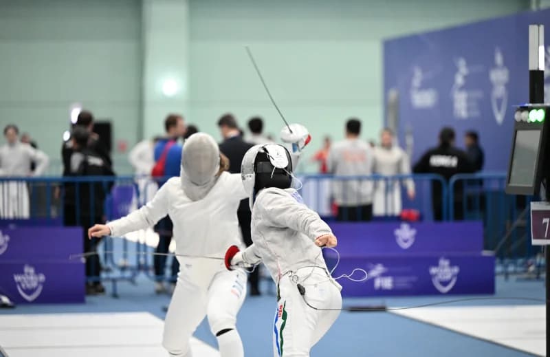 Two athletes competing in fencing