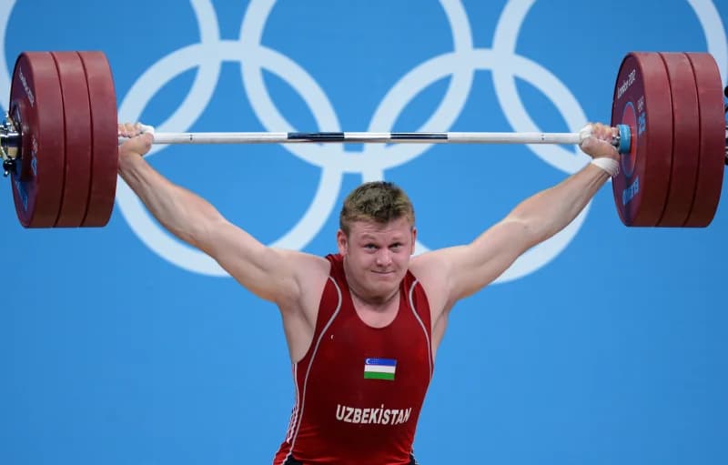 Athlete lifts heavy barbell overhead