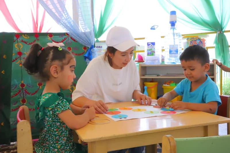 Teacher guiding children with crafts