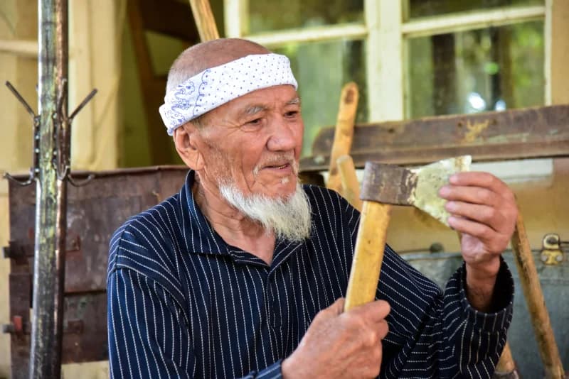 Пожилой мужчина проверяет металлический топор