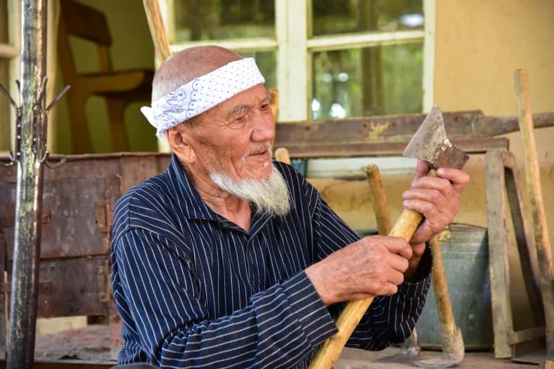 Пожилой мужчина проверяет деревянный инструмент