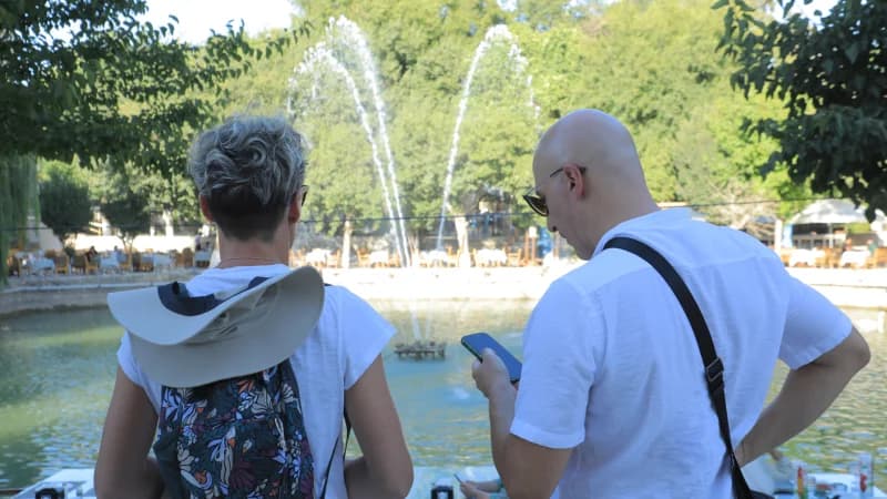 Туристы смотрят на фонтан в парке