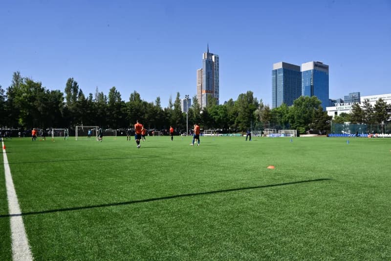 Ochiq futbol maydonida futbolchilar shugʻullanmoqda