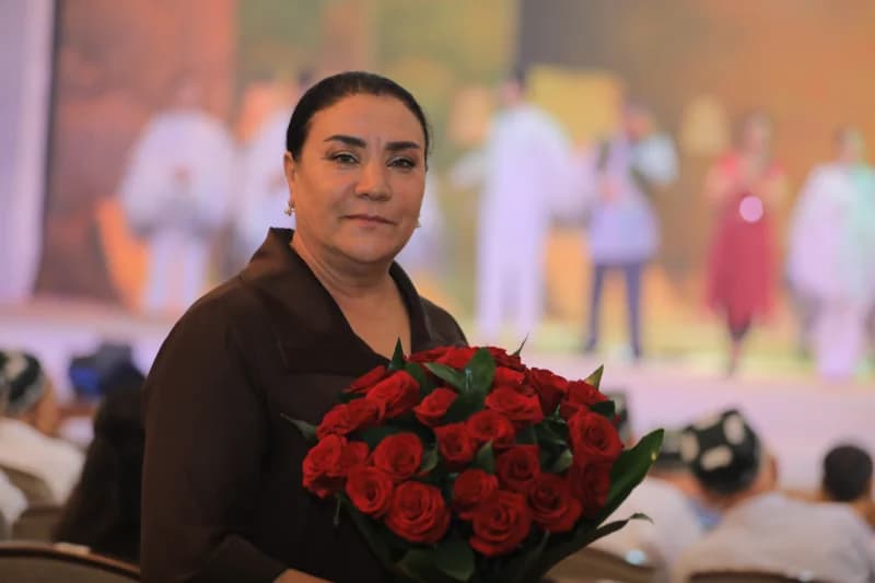Qizil atirgullar guldastasini ushlab turgan ayol