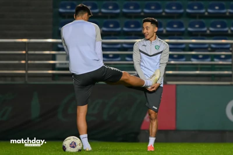 Maydonda choʻzilayotgan futbolchilar.