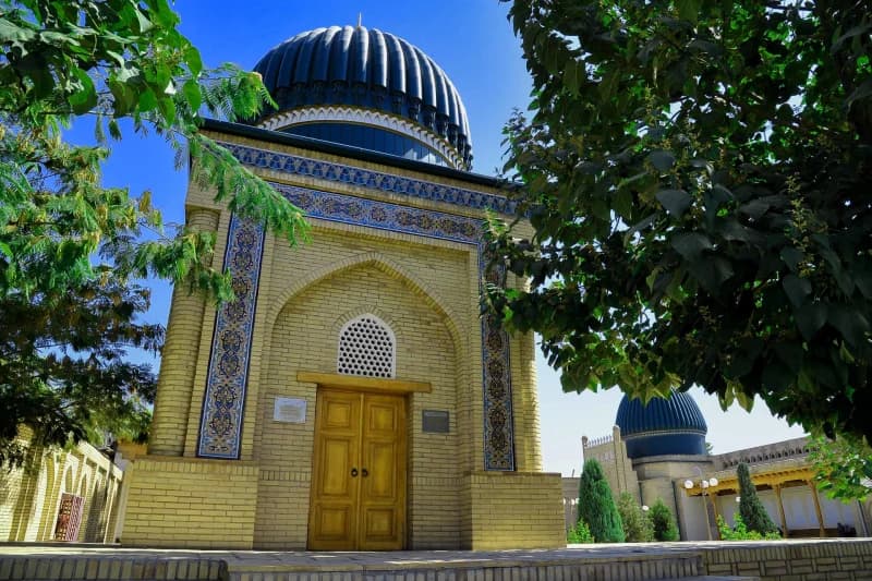 Historic building with blue dome and ornate tiled facade framed by trees