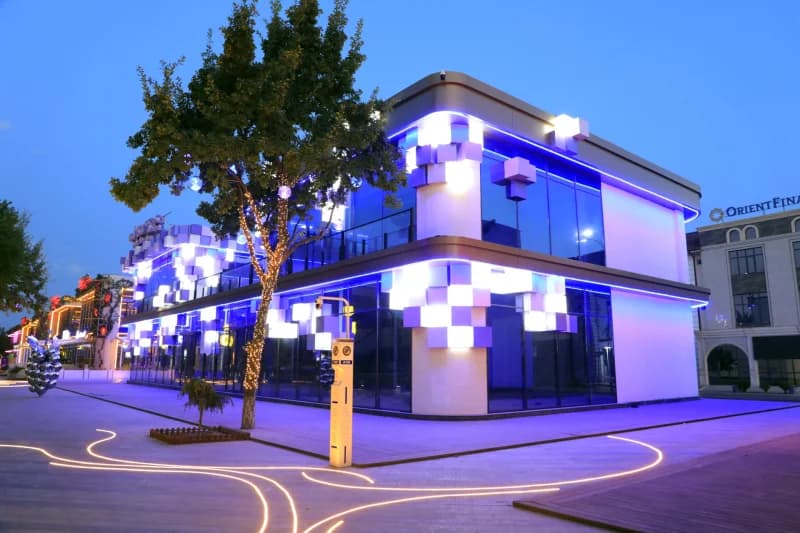Modern illuminated commercial building with blue lighting and cube architectural accents