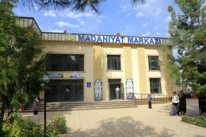 Люди стоят перед зданием, обозначенным видимым текстом