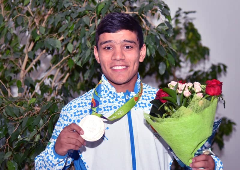 Qoʻlida medal va guldasta ushlab turgan sportchi