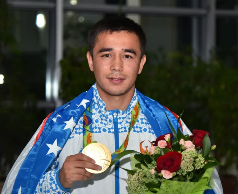 Qoʻlida medal va gul tutgan sportchi