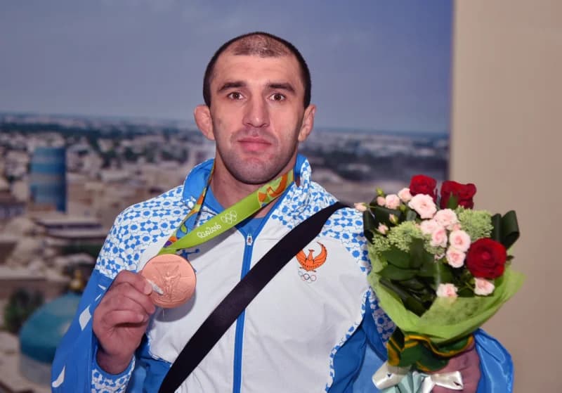 Qoʻlida medal va gul tutgan sportchi