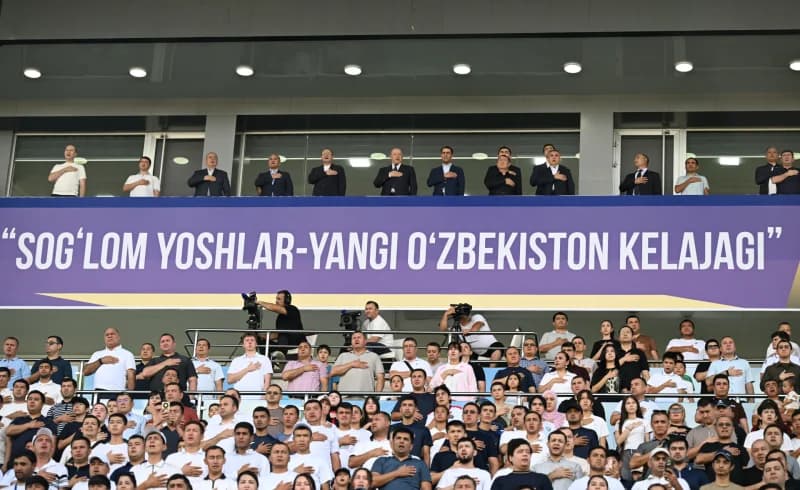 People gathered in a stadium with hands on chests
