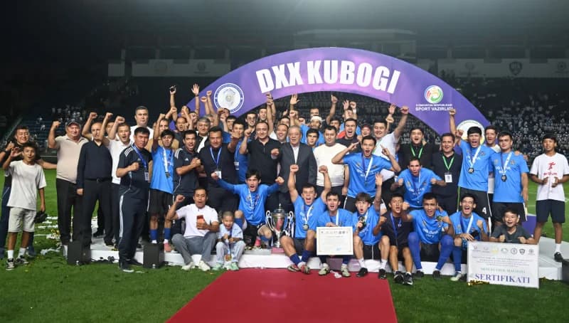 Group of athletes celebrating with trophy on stadium stage