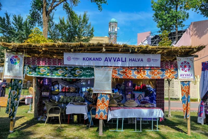 Outdoor trade pavilion displaying sweets and traditional textiles outdoors