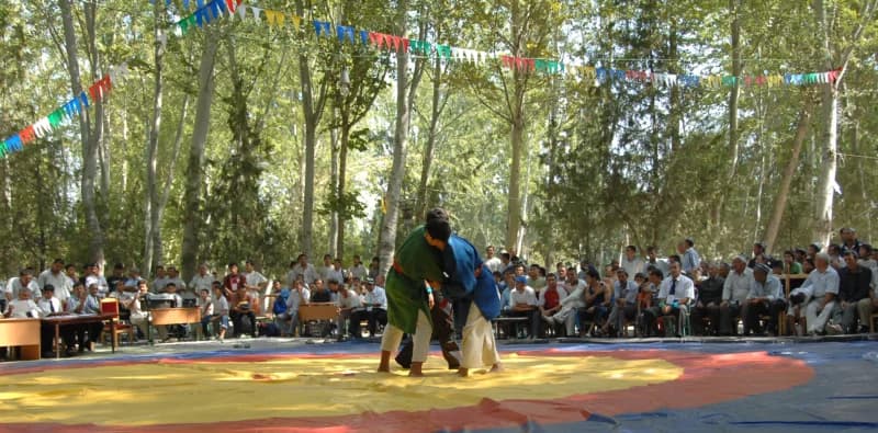 Wrestlers competing on a mat outdoors