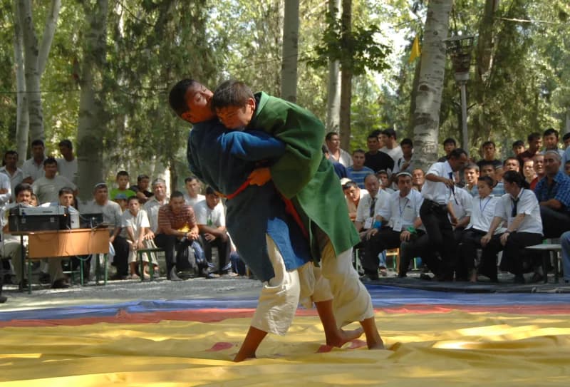 Two competitors grappling on a mat during an outdoor match