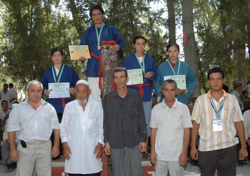 Group of people posing outdoors holding awards and medals