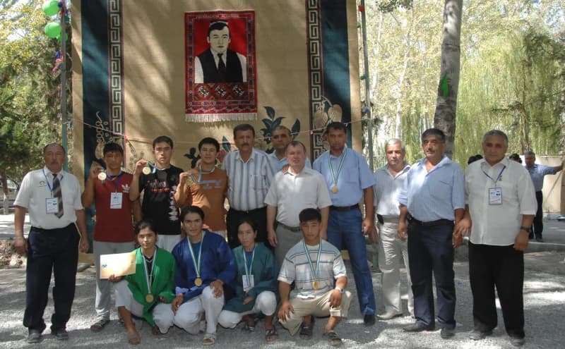 Group portrait of people posing outdoors with medals and certificates