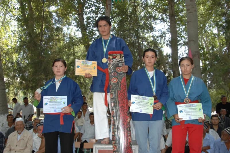 Athletes standing on a podium holding medals and certificates