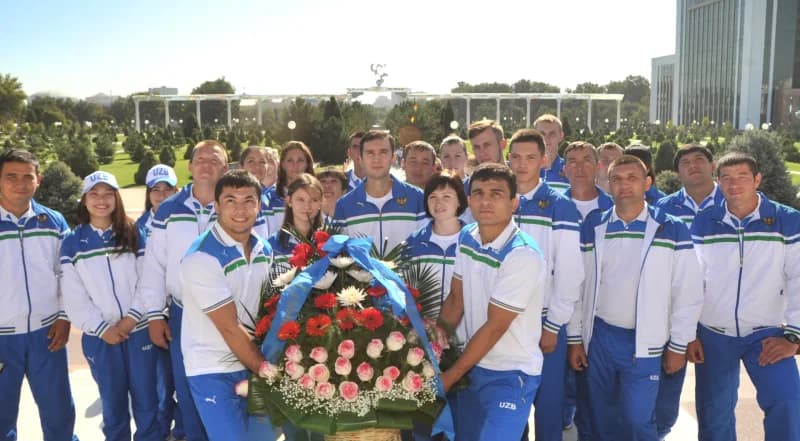 Группа спортсменов в спортивной одежде позирует на открытом воздухе
