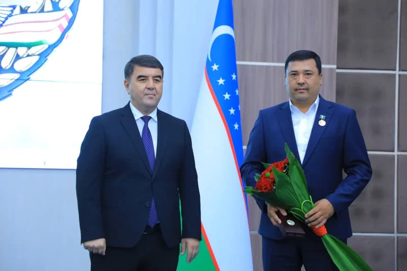 Two men standing next to a national flag