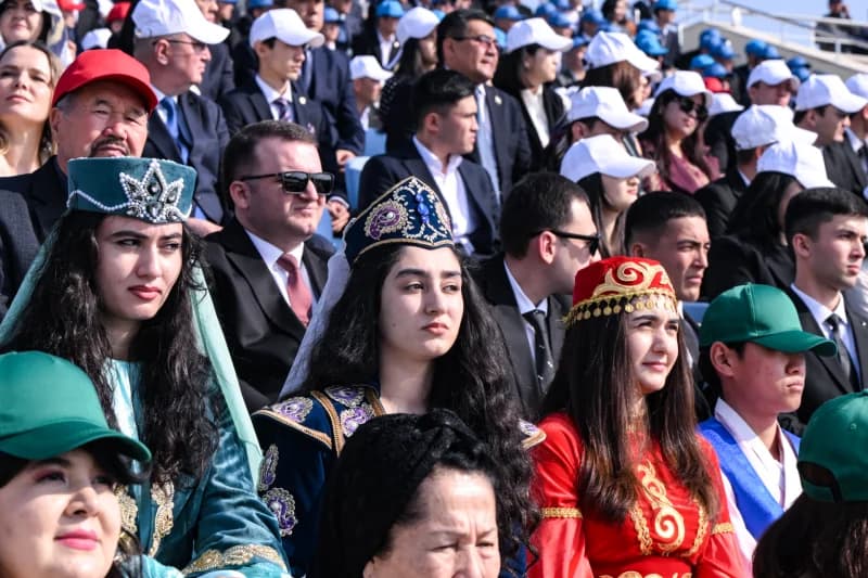 Люди в традиционной одежде, сидящие в толпе во время собрания