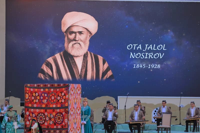 Musicians performing in front of a large screen displaying a historical portrait