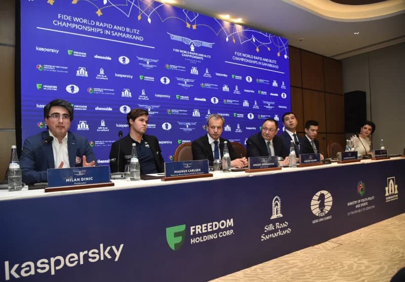 People seated at a panel discussion table with microphones