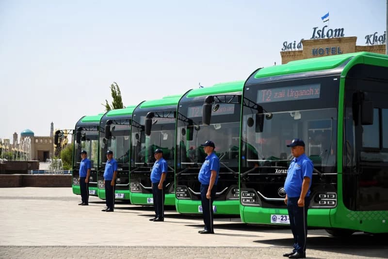 Yashil avtobuslar oldida turgan formali xodimlar