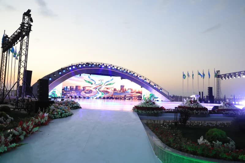 Outdoor stage setup with large LED screen and floral decorations