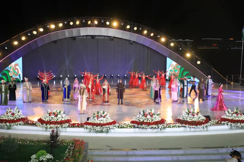 People in traditional clothing performing on a lit outdoor stage at night